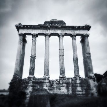 A black and white photo of a set of columns in the Imperial Forum in Rome, Italy.